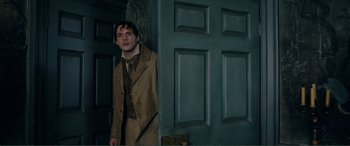 Movie still from “My Cousin Rachel” (2017), directed by Roger Michell – A man standing in front of a green door; Medium shot, Over the shoulder angle