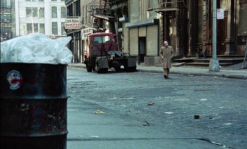Movie still from “My Dinner with Andre” (1981), directed by Louis Malle – A man walking down a street near a garbage truck; Wide shot, High angle