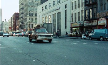 Movie still from “My Dinner with Andre” (1981), directed by Louis Malle – An old truck is driving down the street in the city; Extreme Wide shot, Low angle