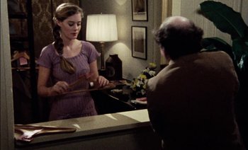 Movie still from “My Dinner with Andre” (1981), directed by Louis Malle – A woman is holding a pair of scissors in front of a man; Medium shot, Over the shoulder angle