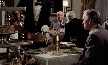 Movie still from “My Dinner with Andre” (1981), directed by Louis Malle – A group of people sitting at a table with wine glasses; Medium shot, High angle