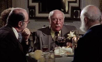 Movie still from “My Dinner with Andre” (1981), directed by Louis Malle – A group of people sitting at a table with wine glasses; Medium shot, Over the shoulder angle