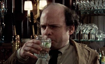 Movie still from “My Dinner with Andre” (1981), directed by Louis Malle – A man drinking a glass of water while sitting at a table; Close Up shot, Over the shoulder angle