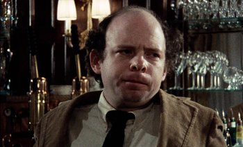 Movie still from “My Dinner with Andre” (1981), directed by Louis Malle – A man with a beard and a tie in front of a wall; Close Up shot, Over the shoulder angle