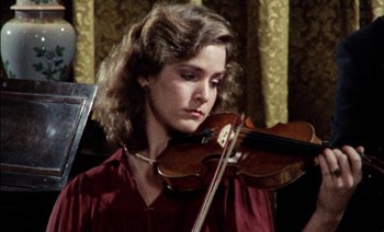 Movie still from “My Dinner with Andre” (1981), directed by Louis Malle – A woman is holding a violin in her hands; Close Up shot, Low angle