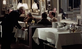 Movie still from “My Dinner with Andre” (1981), directed by Louis Malle – A group of people sitting at a table in a restaurant; Wide shot, Over the shoulder angle