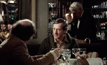 Movie still from “My Dinner with Andre” (1981), directed by Louis Malle – A man sitting at a table in front of another man; Medium shot, Over the shoulder angle
