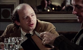 Movie still from “My Dinner with Andre” (1981), directed by Louis Malle – A man sitting at a table with a knife in his hand; Close Up shot, Over the shoulder angle
