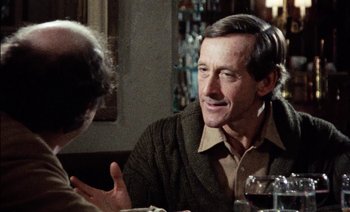 Movie still from “My Dinner with Andre” (1981), directed by Louis Malle – A man sitting at a table talking to another man; Close Up shot, Over the shoulder angle