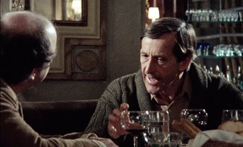 Movie still from “My Dinner with Andre” (1981), directed by Louis Malle – A man sitting at a table with a glass of wine; Close Up shot, Over the shoulder angle