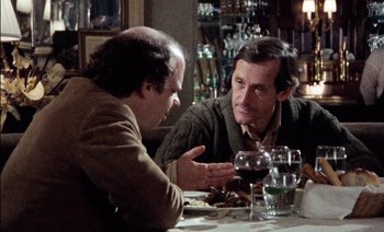 Movie still from “My Dinner with Andre” (1981), directed by Louis Malle – Two men sitting at a table with wine glasses; Medium shot, Over the shoulder angle