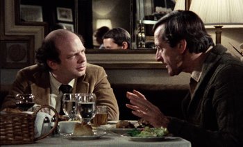 Movie still from “My Dinner with Andre” (1981), directed by Louis Malle – Two men sitting at a table with a plate of food in front of them; Medium shot, Over the shoulder angle