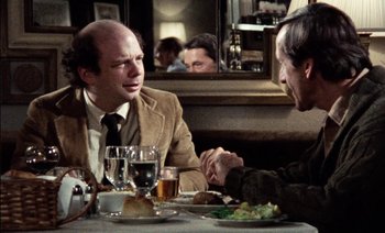 Movie still from “My Dinner with Andre” (1981), directed by Louis Malle – Two men sitting at a table with a plate of food; Medium shot, Over the shoulder angle