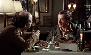 Movie still from “My Dinner with Andre” (1981), directed by Louis Malle – Two men sitting at a dinner table talking to each other; Medium shot, Over the shoulder angle
