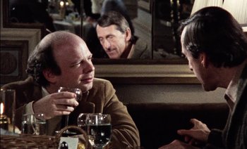 Movie still from “My Dinner with Andre” (1981), directed by Louis Malle – A man sitting at a table in front of two other people; Close Up shot, Over the shoulder angle