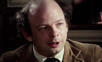 Movie still from “My Dinner with Andre” (1981), directed by Louis Malle – A man with a bald head is sitting in a chair; Close Up shot, Over the shoulder angle