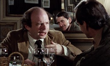 Movie still from “My Dinner with Andre” (1981), directed by Louis Malle – A man sitting at a table in front of a glass of wine; Close Up shot, Over the shoulder angle