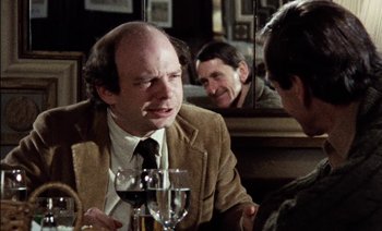 Movie still from “My Dinner with Andre” (1981), directed by Louis Malle – A man sitting at a table with a glass of red wine; Close Up shot, Over the shoulder angle
