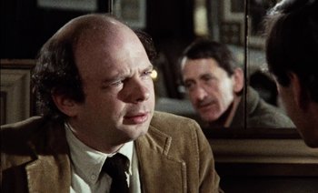 Movie still from “My Dinner with Andre” (1981), directed by Louis Malle – A man in a suit and tie next to another man in a suit and tie in front of a mirror; Close Up shot, Over the shoulder angle