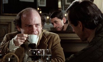 Movie still from “My Dinner with Andre” (1981), directed by Louis Malle – A man sitting at a table drinking a cup of coffee; Close Up shot, Over the shoulder angle