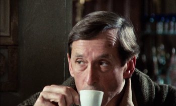 Movie still from “My Dinner with Andre” (1981), directed by Louis Malle – A person drinking a cup of coffee; Close Up shot, Over the shoulder angle