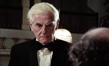 Movie still from “My Dinner with Andre” (1981), directed by Louis Malle – An older man in a tuxedo looking at the camera; Close Up shot, Low angle