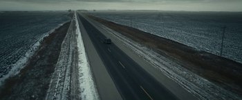 Movie still from “Fractured” (2019), directed by Brad Anderson – A car driving down a road in the middle of a snowy field; Extreme Wide shot, High angle