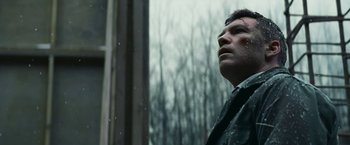 Movie still from “Fractured” (2019), directed by Brad Anderson – A man looking out of a window at a forest; Close Up shot, Low angle