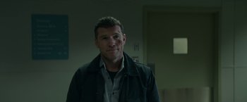 Movie still from “Fractured” (2019), directed by Brad Anderson – A person wearing a jacket in a room; Close Up shot, Over the shoulder angle