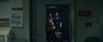 Movie still from “Fractured” (2019), directed by Brad Anderson – A man , woman , and a child are standing in an elevator; Medium shot, Low angle