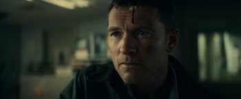 Movie still from “Fractured” (2019), directed by Brad Anderson – A person with a cross on his forehead; Close Up shot, Low angle