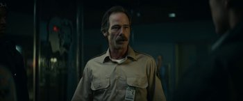 Movie still from “Fractured” (2019), directed by Brad Anderson – A man with a mustache wearing a tan shirt; Close Up shot, Low angle