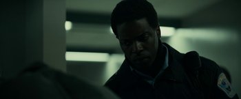 Movie still from “Fractured” (2019), directed by Brad Anderson – A man looking down at something in a dark room; Close Up shot, Over the shoulder angle