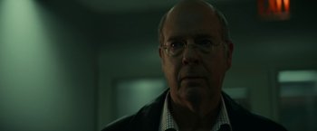 Movie still from “Fractured” (2019), directed by Brad Anderson – An older man wearing glasses looking at the camera; Close Up shot, Low angle