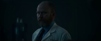 Movie still from “Fractured” (2019), directed by Brad Anderson – A man in a lab coat and a tie; Close Up shot, Low angle