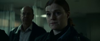 Movie still from “Fractured” (2019), directed by Brad Anderson – A woman in a dark room looking at the camera; Close Up shot, Over the shoulder angle