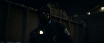 Movie still from “Fractured” (2019), directed by Brad Anderson – A police officer is holding a flashlight in the dark; Close Up shot, Low angle