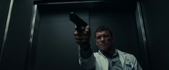 Movie still from “Fractured” (2019), directed by Brad Anderson – A man is holding a gun in a dark room; Close Up shot, Low angle