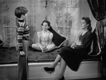 Movie still from “My Favorite Wife” (1940), directed by Garson Kanin – A woman and two young children sitting on a bed; Wide shot, High angle