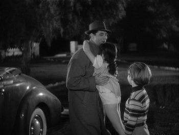 Movie still from “My Favorite Wife” (1940), directed by Garson Kanin – An old photo of a man and two children hugging; Medium shot, High angle