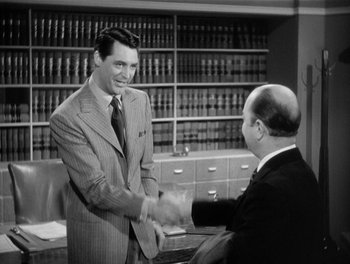 Movie still from “My Favorite Wife” (1940), directed by Garson Kanin – A man shaking hands with another man in a suit; Medium shot, Over the shoulder angle