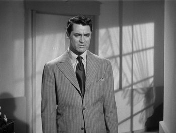 Movie still from “My Favorite Wife” (1940), directed by Garson Kanin – A man wearing a suit and tie standing in front of a window; Medium shot, Over the shoulder angle