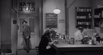 Movie still from “My Gun Is Quick” (1957), directed by Victor Saville – A woman sitting at a counter in a restaurant; Wide shot, Over the shoulder angle
