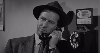 Movie still from “My Gun Is Quick” (1957), directed by Victor Saville – A black and white photo of a man talking on a phone; Close Up shot, Low angle