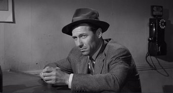 Movie still from “My Gun Is Quick” (1957), directed by Victor Saville – A man wearing a suit and a hat; Close Up shot, High angle