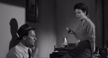 Movie still from “My Gun Is Quick” (1957), directed by Victor Saville – A man and a woman sitting in front of each other in a room; Medium shot, Low angle