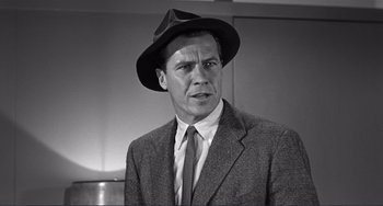 Movie still from “My Gun Is Quick” (1957), directed by Victor Saville – Black and white photograph of a man wearing a suit and a hat; Close Up shot, Low angle