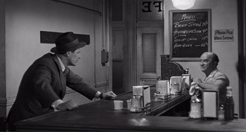 Movie still from “My Gun Is Quick” (1957), directed by Victor Saville – A black and white photo of a man at a bar; Medium shot, High angle