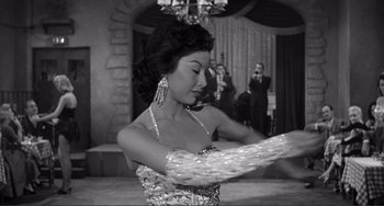 Movie still from “My Gun Is Quick” (1957), directed by Victor Saville – A woman in a silver dress is holding a fan in her hand; Medium shot, Low angle
