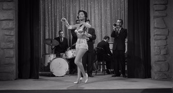 Movie still from “My Gun Is Quick” (1957), directed by Victor Saville – A woman in a white dress is performing on a stage; Wide shot, Low angle